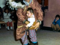 1950s A mother putting baby on her back underneath the parka. Wolf and wolverine ruff.