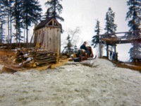 1960s Gary Bringing in a load of wood with our snow traveler. Outhouse in background.