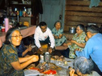 1960s Meal time in Kiana.  Dora Johnson on the left.  Eating frozen fish, dried fish, and seal oil.