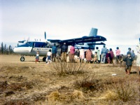 Late 1060s. Twin Otter mail plane on dirt strip behind town.