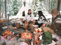 Oliver, Heidi and one other sitting around campfire. Teepee in background. Norway